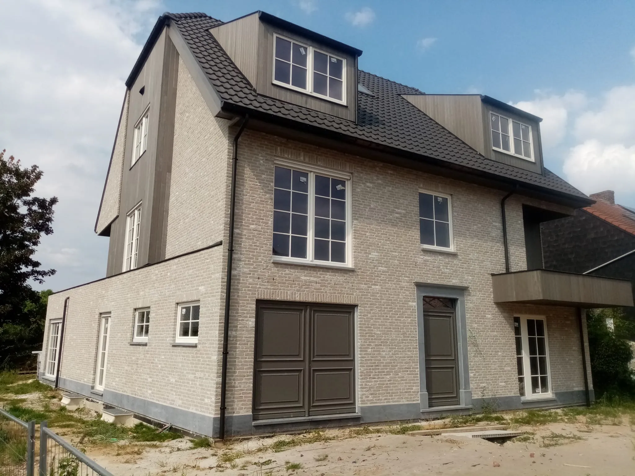 Achtergevel met dakkapellen en terras van de appartementen in Holsbeek