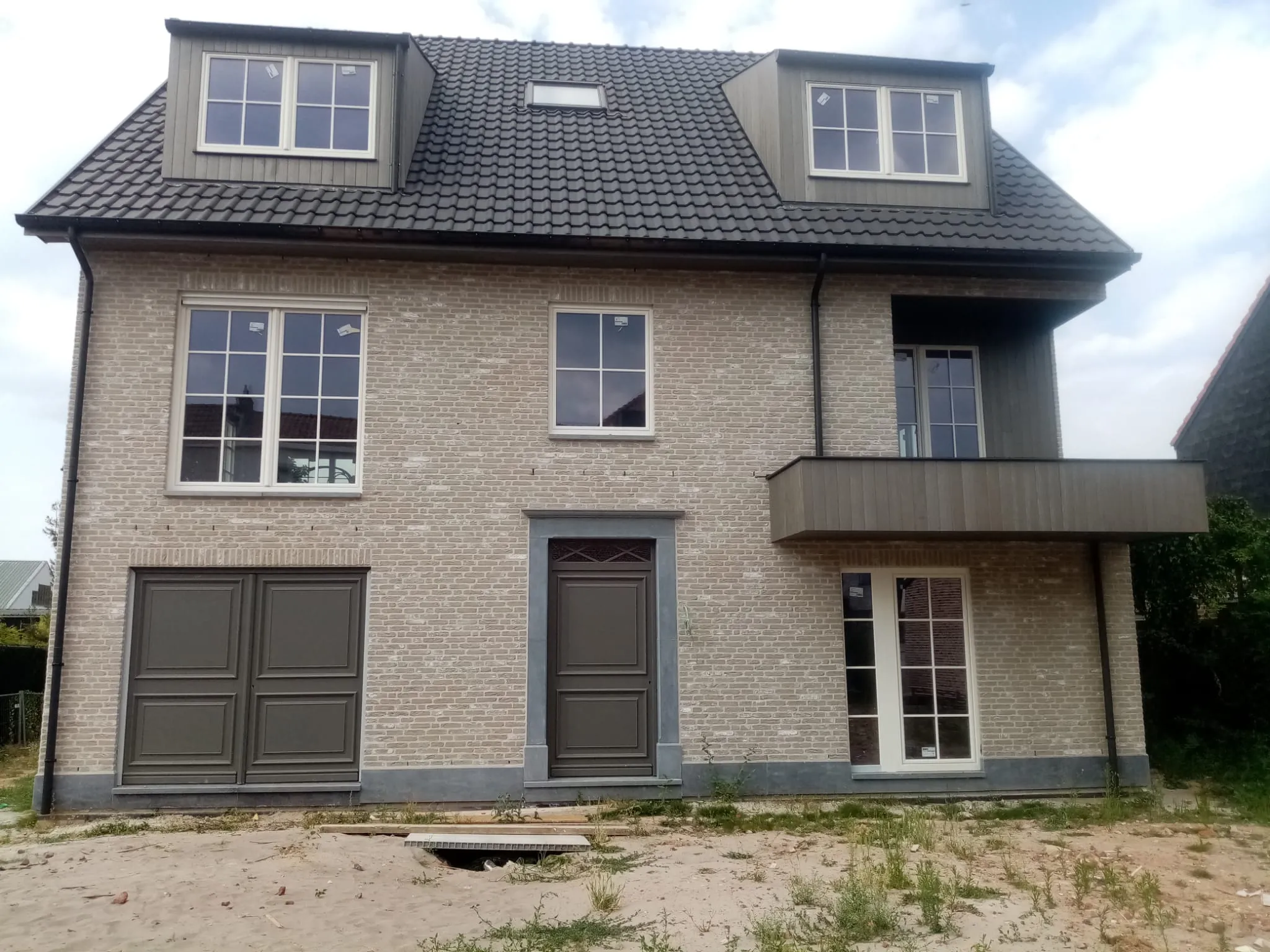 Achtergevel met inkom en balkon van de meergezinswoning in Holsbeek